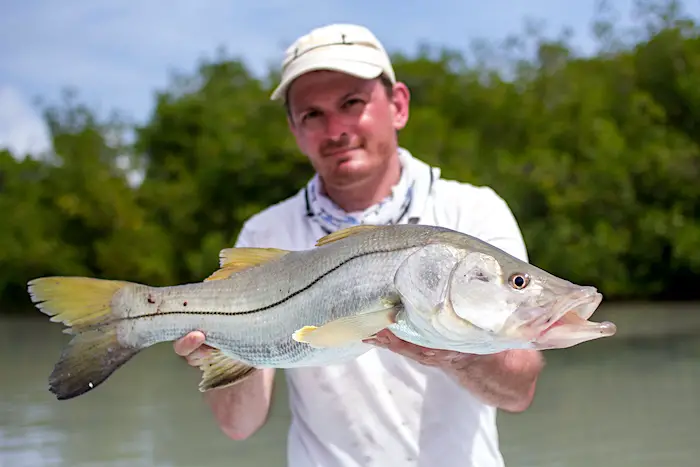 Florida angler holding a big keeper snook caught on rod and reel inshore.