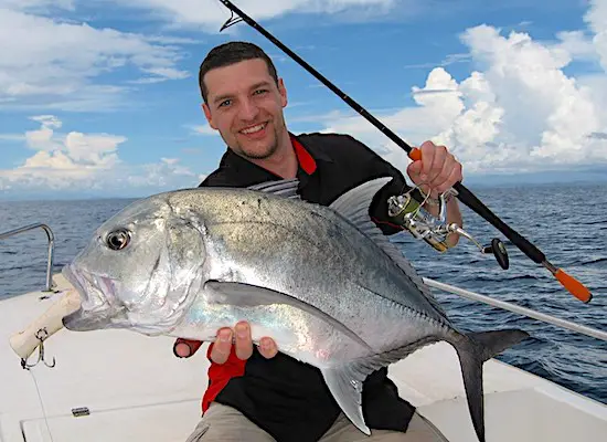 Man holding big jack crevalle fish he caught in Florida from a boat.