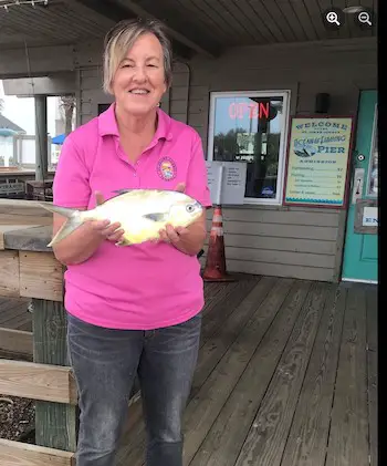 St Johns County Ocean Fishing Pier customer service rep Kathryn holding a pompano caught at this St. Augustine fishing pier.